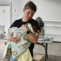 Caregiver comforting an animal wrapped in a blanket during post-op recovery